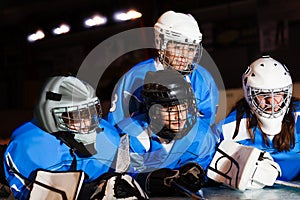 Happy teenage hockey players laying on ice rink