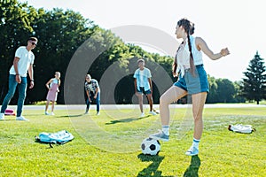 happy teenage multiethnic friends playing with soccer ball in park