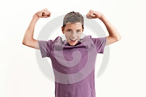 Happy teenaged disabled boy with cerebral palsy smiling at camera and raising clenched fists, feeling strong, posing