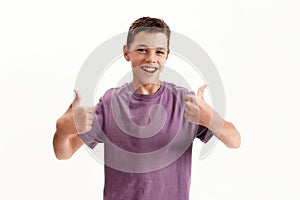 Happy teenaged disabled boy with cerebral palsy smiling at camera and showing thumbs up with both hands, posing isolated