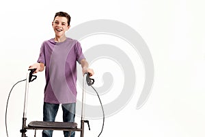 Happy teenaged disabled boy with cerebral palsy smiling at camera, taking steps using his walker isolated over white