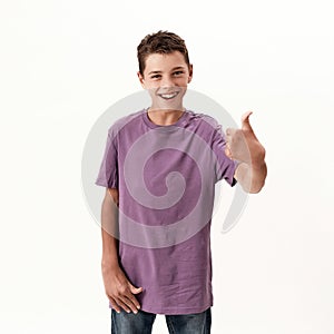 Happy teenaged disabled boy with cerebral palsy smiling and showing thumbs up at camera, posing isolated over white