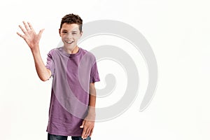 Happy teenaged disabled boy with cerebral palsy smiling and waving at camera, posing isolated over white background