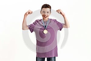 Happy teenaged disabled boy with cerebral palsy wearing gold medal, smiling at camera, raising clenched fists, feeling