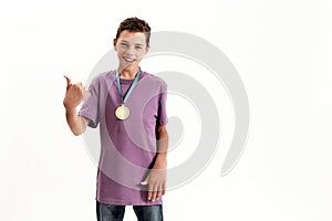 Happy teenaged disabled boy with cerebral palsy wearing gold medal, smiling and showing thumbs up at camera, standing