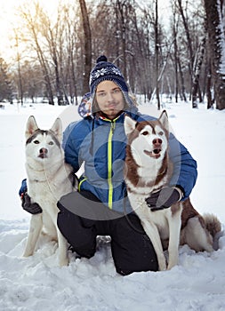 Happy teenager boy playing with white Husky dog in winter day, dog and child on snow