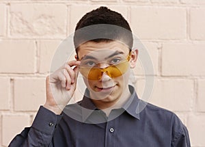 Happy teenager boy in sun glasses closeup portrait on white wall background