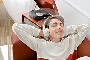 Happy teenager boy wearing earphones listening music, enjoying and having fun. Retro wooden turntable with vinyl record on