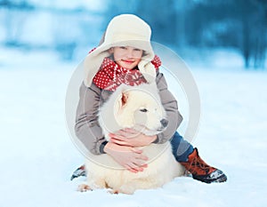 Happy teenager boy with white Samoyed dog outdoors in winter day