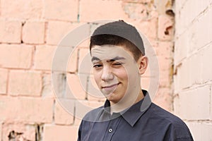 Happy teenager boy wink closeup portrait on white wall background