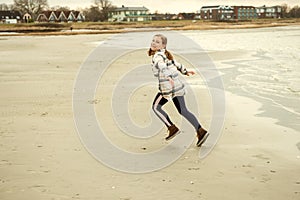 Happy teenager child girl walking and playing on Baltic sea beach