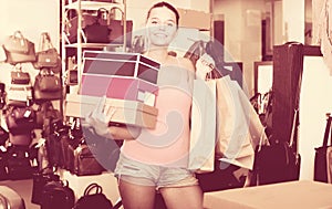 Happy teenager female holding boxes in shoes boutique