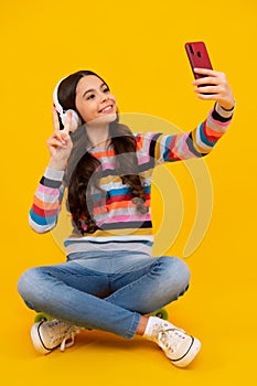 Happy teenager girl 12, 13, 14 years old with smart phone. Hipster teen girl types message on cellphone, enjoys mobile