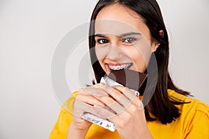 Happy teenager girl with metal orthodontics biting a chocolate bar