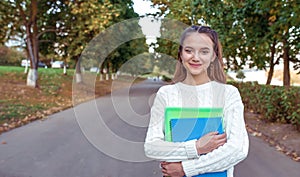 Happy teenager girl smiling cheerful joyful, stands summer park autumn trees background, free space for copy text. In