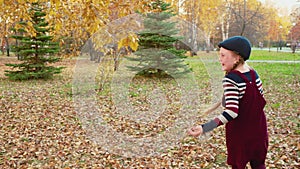 Happy teenager girl throwing bouquet from yellow maple leaves in park. Cheerful girl catching autumn bouquet from fallen