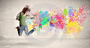 Happy teenager jumping with colorful ink splatter on urban background