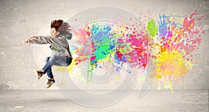 Happy teenager jumping with colorful ink splatter on urban background