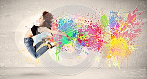 Happy teenager jumping with colorful ink splatter on urban background