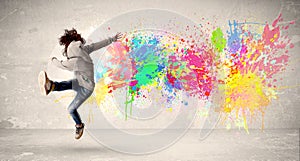 Happy teenager jumping with colorful ink splatter on urban background