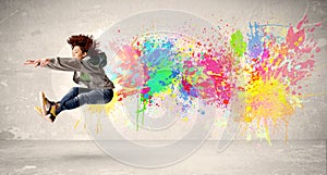 Happy teenager jumping with colorful ink splatter on urban background