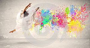 Happy teenager jumping with colorful ink splatter on urban background