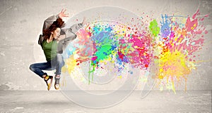 Happy teenager jumping with colorful ink splatter on urban background