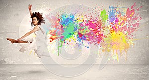 Happy teenager jumping with colorful ink splatter on urban background