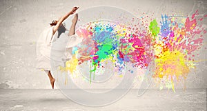 Happy teenager jumping with colorful ink splatter on urban background