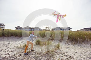 Happy teenager running and having fun with kite on beach