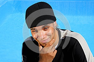 Happy teenager sitting at swimming pool