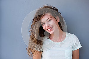 Happy teenager smiling against gray wall