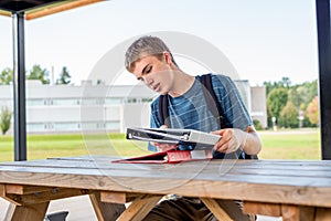 Happy teenager studying outdoors at a picnic table.