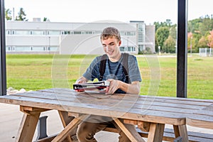 Happy teenager studying outdoors at a picnic table.