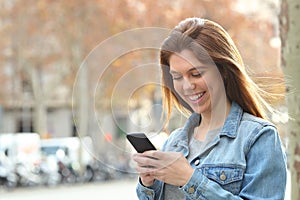 Happy teenager texting on phone walking in the street