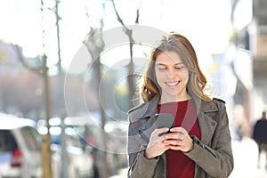 Happy teenager walks using a smart phone in the street