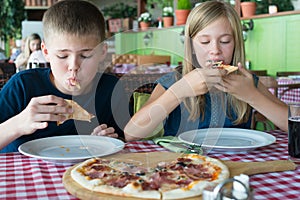 Feliz adolescentes comer una hoja circular grande de masa ligera en cafetería. amigos o hermanos divirtiéndose en un restaurante 