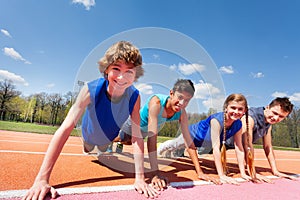 Happy teenagers holding plank outdoor on the track