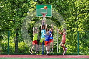 Happy teenagers playing basketball on playground