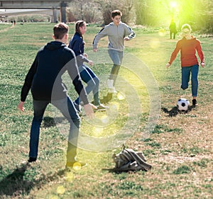 Happy teenagers playing football on green lawn