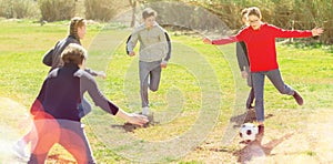 Happy teenagers playing football on green lawn