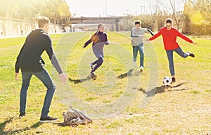 Happy teenagers playing football on green lawn