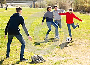 Happy teenagers playing football on green lawn