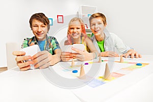 Happy teenagers playing table game holding cards