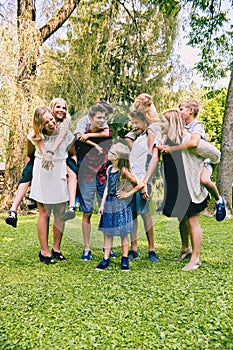 Happy teenagers riding piggyback little siblings