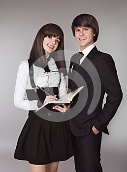 Happy teenagers in school uniform portrait. Handsome boy and beautiful brunette girl posing isolated on studio background.