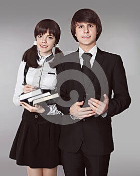 Happy teenagers in school uniform portrait. Handsome boy and beautiful brunette girl posing isolated on studio background.