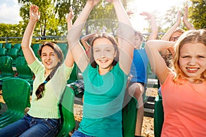 Happy teens hold arms up during game on tribune