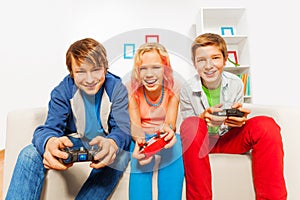 Happy teens hold joysticks and play game console