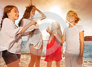 Happy teens holding sparklers during beach party